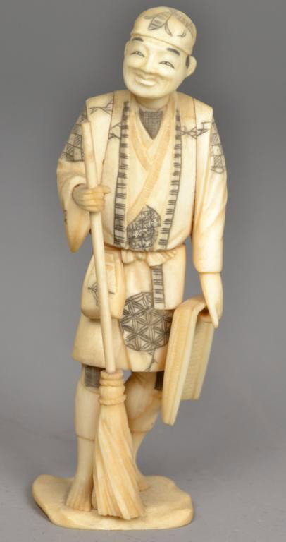 A Fine Japanese Ivory Okimono Of A Sweeper: Probably Meji period, finely carved to depict a man holding a broom and dustpan, two character mark to underside, with inked and dyed elements, measures 7" H. Private collection Oxford MI.