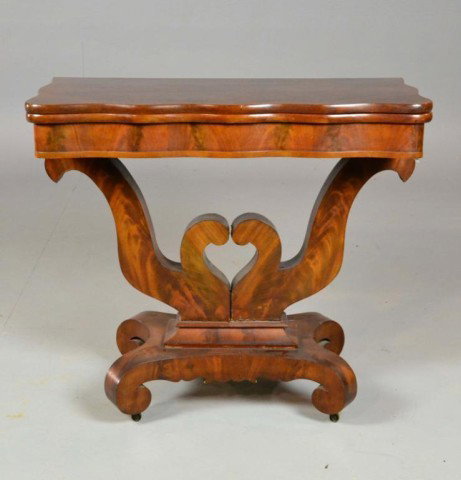 A New York Classical Fold Over Card Table: The mahogany wood with serpentine fold over swivel top above heart shaped column and raised on four scrolling supports with casters, 29.5" H x 24" L. Circa 19th century. Private collection Oxford, Mic