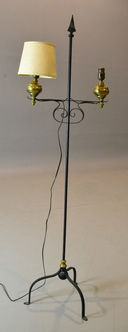 Early American Wrought Iron And Brass Candlestand: Original candlestand converted into a lamp with round center column, arrow finial, two brass lights and resting on three shaped legs. 64" H. Private collection Bloomfield Hills, Mi.