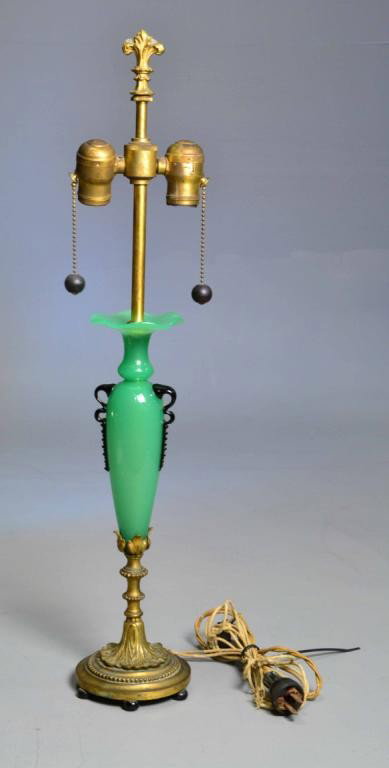 ART DECO OPALINE LAMP WITH BRASS BASE: Exquisite art deco lamp, fleur de lis brass top, decorative base with elaborate scrolling, rising to anchor opaline, opaque, hand-blown green base, with two black ornate decorative mimic handles, six