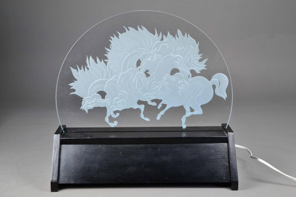 LIGHTED GLASS SCULPTURE OF HORSES: Demi-lune circular glass etched with a group of three lively horses, set in lighted black base, glass diameter is 20" and 1/2" thick, base 5.5" H x 20" L, signed on glass , excellent condition. Privat