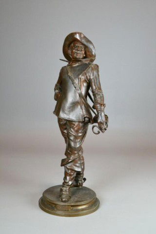 Edouard Drouot Bronze of a Musketeer: Finely cast to depict a standing musketeer with feathered hat upon a circular base, signed to top of base, Edouard Drouot (1859-1945) was a French artist known for his sculpture, 28.5" H, circa late 1