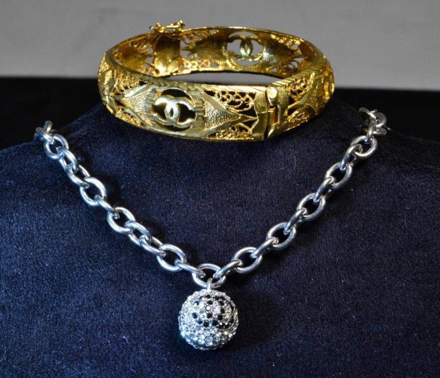 (2) Ladies Chanel Bracelets: To include a gold tone open filigree bangle with cc logo and a silver tone chain link bracelet with crystal ball charm and cc logo.