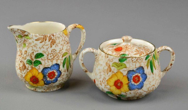 CHINTZWARE CREAM & SUGAR - J. KENT: Matching cream and covered sugar, brightly colored floral design on brown transfer vining design with gold on rims, Fenton, England, early 18th century, 3.75" H creamer, 2.5" H x 4.5" L sugar bowl, ex
