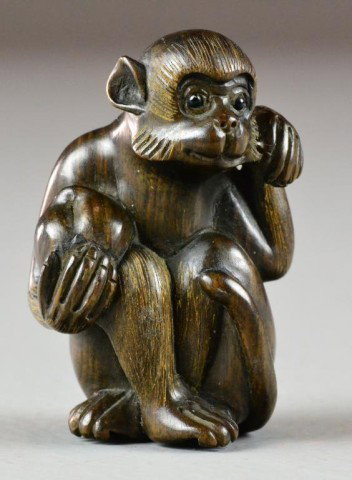 A Fine Japanese Carved Boxwood Netsuke: Finely carved of dark boxwood, depicting a seated monkey holding a coconut, signed to ivory plaque to base, wonderfully executed, 2.25"H, circa late 19th/ early 20th century.