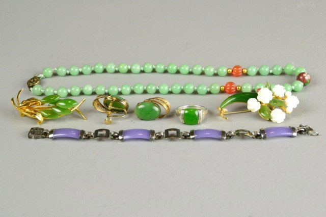 (7) Pcs. Chinese Jade Jewelry: To include a celadon green bead necklace with silver clasp and cinnabar and red stone accents, a lavender jade a silver mounted bracelets, two spinach jade broaches, one with ivory and coral highlight