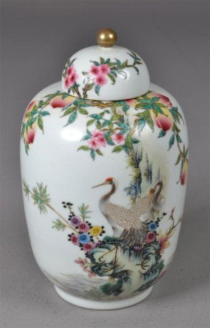 Chinese Covered Famille Rose Porcelain Vase: Covered porcelain ginger jar having gold knob finial and enamelled decoration depicting peach blossoms and tree, peaches and two cranes, blue underglazed seal, 11 H x 6" Diameter.