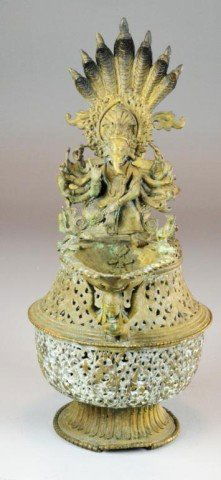 Large Tibetan Ewer Form Butter Lamp: Intricately carved large bronze ewer-shaped Tibetan butter lamp, reticulated body, braided handle mounted with peacock and seven cobras, lamp holder supported by female and decorated with Ganesh and t