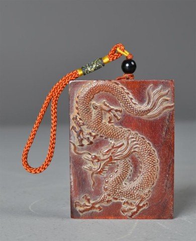Chinese Ox Horn Dragon Pendant: Finely carved to depict a four clawed dragon hanging from a red cord with onyx colored bead, 2.75"H X 2.125"W, circa late 19th/early 20th century. Private collection.