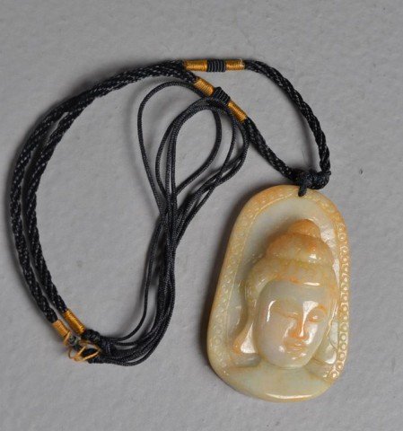 Chinese Carved Jade Buddha Pendant: Finely carved and polished pendant depicting the face of Buddha in light green to iron red jade, 1" W x 2" L x .75" D. Private collection Rochester Hills, MI.