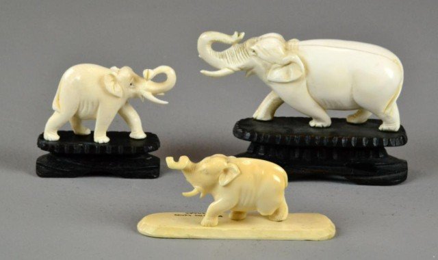 (3) Chinese Carved Ivory Elephants: All standing with raised trunks, two carved with hardwood stand, and one with ivory stand, largest meaures 4.25" L, smallest lacking one leg, circa 20th century.