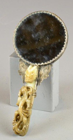 Chinese Jade Mounted & Silver Hand Mirror: With jade mounted handle finely carved to depict a dragon with climbing chilong, the silvered metal finely moulded to depict a sinous amongst ruyi clouds, chasing a flaming pearl, jade handle measures