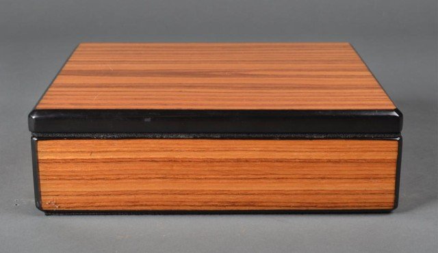 A Fine French Wood Humidor: Wood case with black lacquered edges, interior cedar lined and with hydrogmeter and humidifier. 3.5" H x 11" W x 9 & 7/8" D. Hydrometer stamped Made in France, filter monogramed MH. Excellent conditio