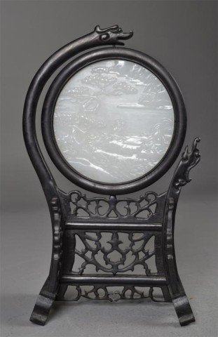 Chinese Carved White Hardstone with Holder: Circular finely carved white hardstone depicting scene of man and woman seated in landscape, 5.5" Diameter, reticulated holder of carved ebonized wood with three dragons, 13" H x 7" W x 4.5" D. Privat