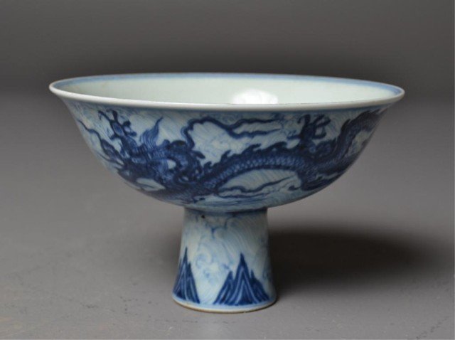 Chinese Ming Blue and White Porcelain Stem Cup: Ming style blue and white stem cup having mountain decoration on stem, flying dragon and wave design on body, blue marks in center of bowl within double concentric circles, 4" H x 6.25" Diameter.