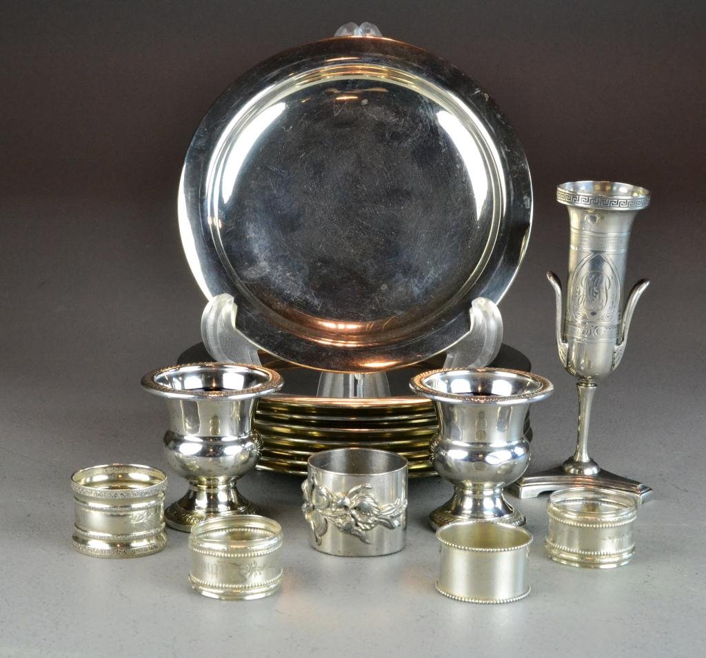 (16) Pcs. Sterling and Silverplate: Consisting of two weighted sterling silver urn-shaped salt cellars with cobalt blue glass liners, 2.75" H, one repousse stainless napkin ring, eight footed silverplate underplates 7" Diameter, an unus