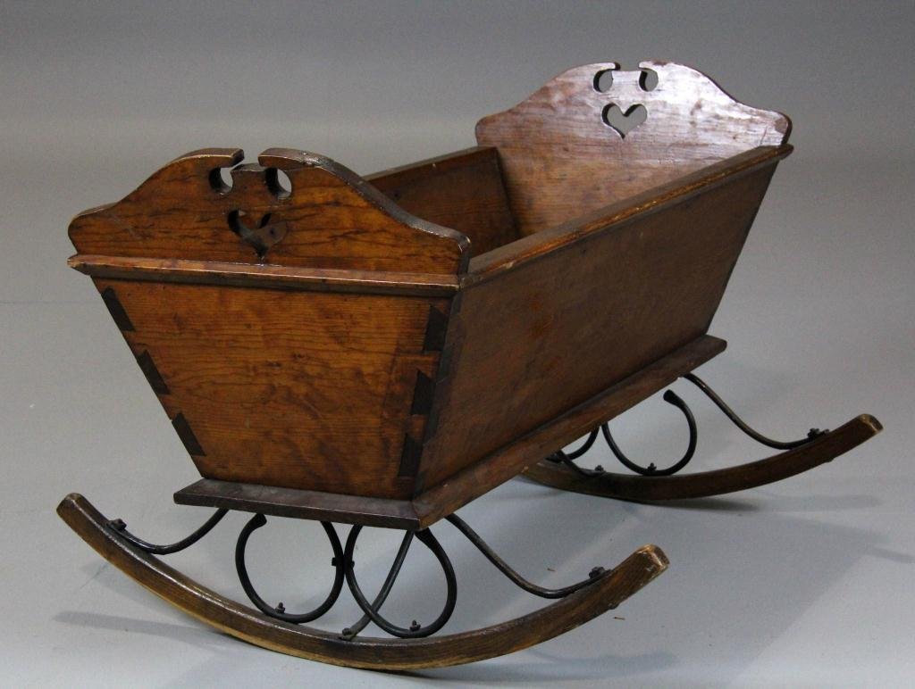 American Pine & Iron-mounted Baby Cradle: With finely cut dovetail sides, two heart-shaped cutouts, with scroll-shaped hand-wrought iron supports, 37" L x 22.5" H x 25.5" D, circa early 19th Century, condition: normal nicks and abrasions comm