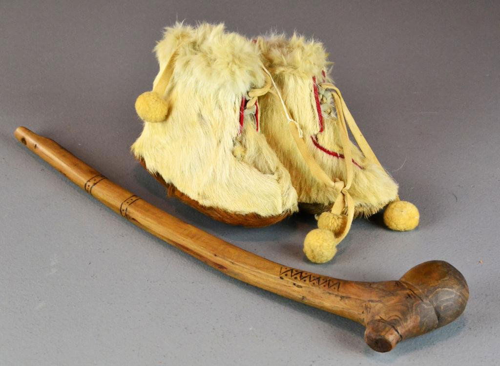 (2) Native American Items Including A Scullcracker: To include a pair of childs Native American fur boots with tassels and a hand carved wooden skull cracker. Largest measures 19" long. Circa early 20th century.