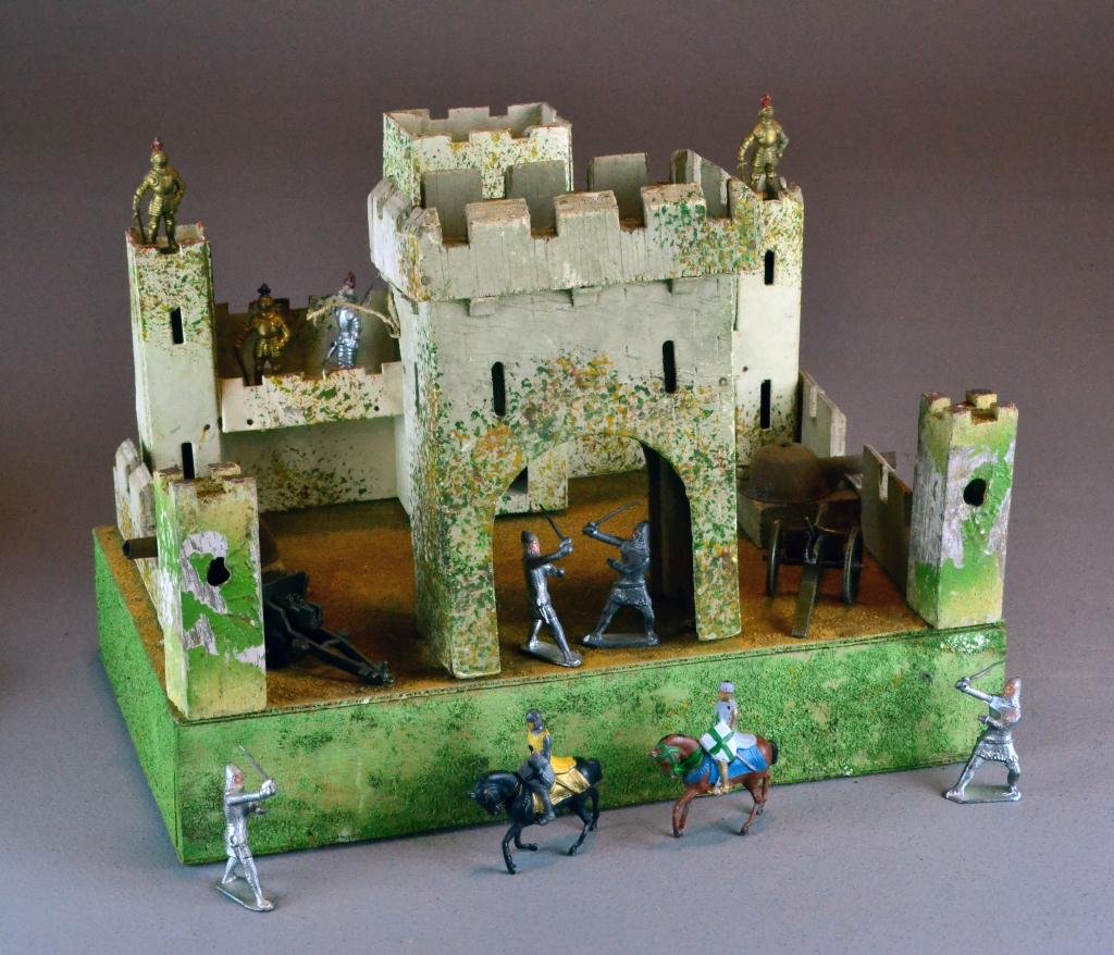A British Model Of A Fort & 14 Toy Soldiers: A wood and painted model of a British fort with two iron drum-form cannons mounted to each side together with fouteen metal soldiers and cannons, 12" H x 16" W x 9,5" D, circa early 20th century.