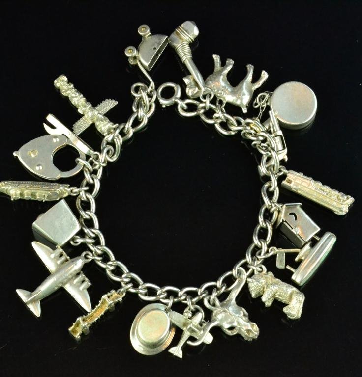 A Fine Sterling Silver Charm Bracelet: Consisting of a 7" sterling chain and a unique grouping of fine charms: Titanic, pram, moveable teddy bear, airplane, London Bridge, hinged outhouse, locomotive, Indian skull cracker, round flask, top