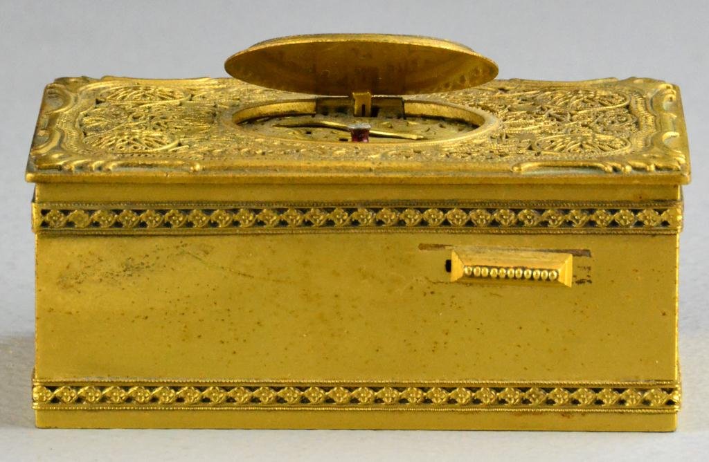 Continental Bronze Music Box - Karl Griesbaum: Having pierced gilt grill, C-scroll lid border, stop/start button to right-hand side, suburst oval medallion hinged opening, marked on bottom with bird above mountains and letter G., 1.5" H x 4" W x 2