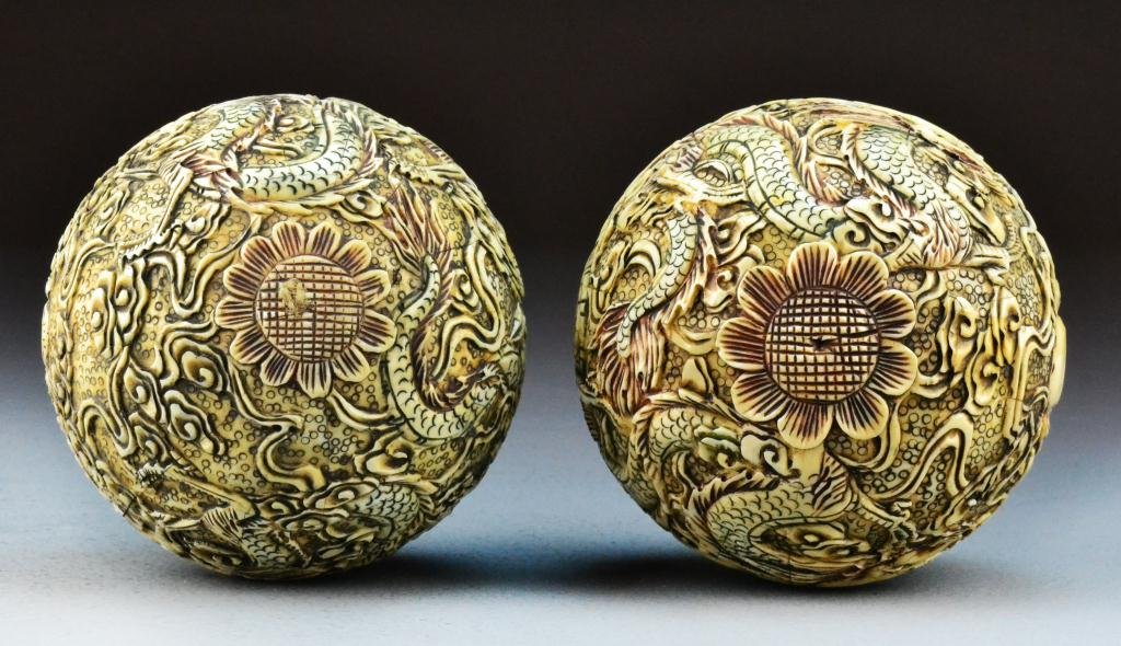 Pr. Chinese Carved Bone Spherical Balls: Finely carved to depict dragons chasing a flaming pearl amongst ruyi clouds, with polychrome painted decoration throughout, 5.125" Diameter, circa early 20th century. Private collection Wyandotte Mich
