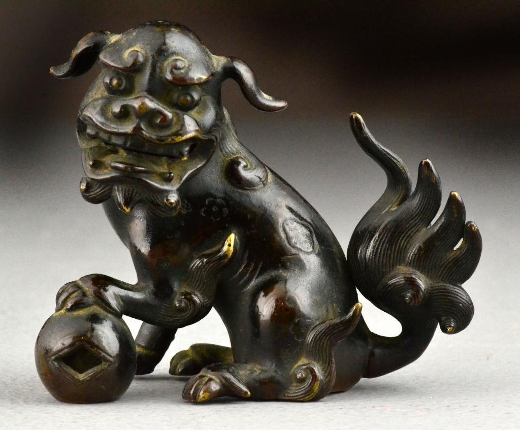 Chinese Qing Bronze Buddhist Foo Lion: Finely carved to depict a foo lion, better known as a foo dog, with furled tail and his paw on a ball indicating maleness, 3.25"H, circa 19th century. Provenance: Once part of the Zernikow Collection.