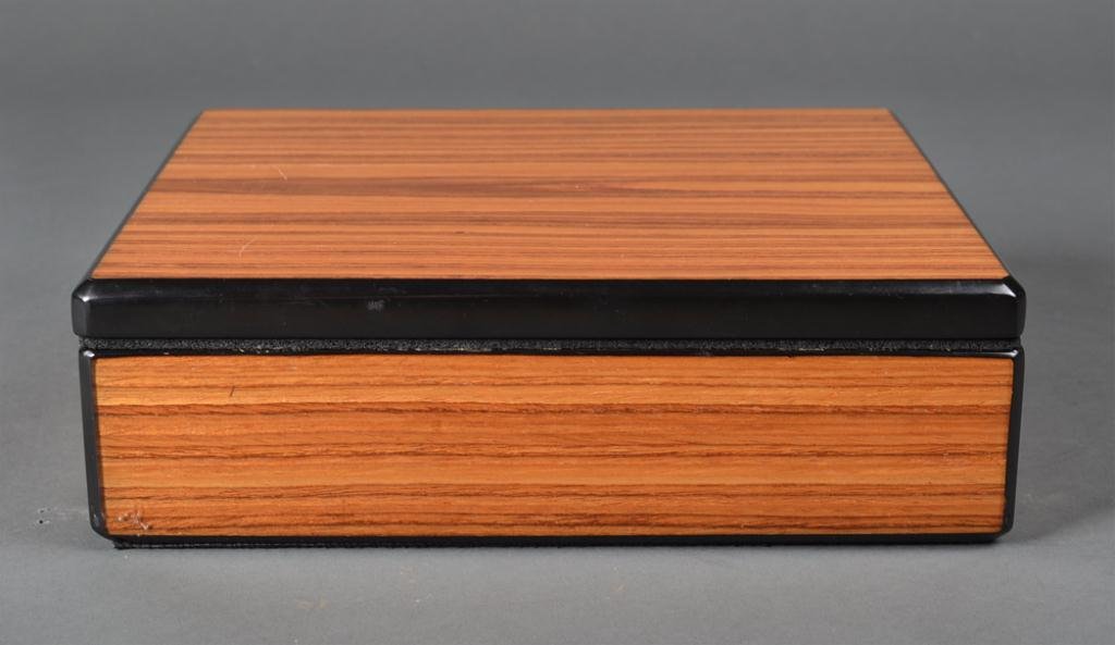 A Fine French Wood Humidor: Wood case with black lacquered edges, interior cedar lined and with hydrogmeter and humidifier. 3.5" H x 11" W x 9 & 7/8" D. Hydrometer stamped Made in France, filter monogramed MH. Excellent conditio