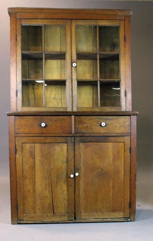 American Pine Step-Back Cupboard: Very nice pine cupboard with molded front cornice, two six-paned glazed doors with one porcelain knob, opening to reveal two inside wooden shelves, above two dovetailed dovetailed drawers with porcela
