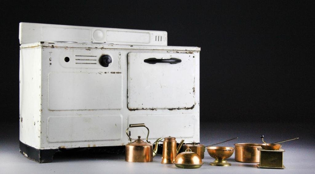 (8) Antique Electric Toy Stove & Toy Copper Pots: A white stove with 4 burners and an oven 11" H x 13" W x 7" D. Also included 7 toy pots and kitchen utensils. Condition: some paint loss otherwise the stove is in working order and the burners heat up