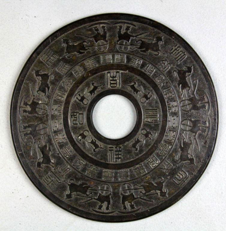 Large & Fine Chinese Archaic Style Jade Bi-Disc: The dark almost black stone finely carved on both sides to depict horses pulling figures in a covered cart, with many lines of calligraphy, 11.75"D, circa late 19th/early 20th century or earlier. Prop
