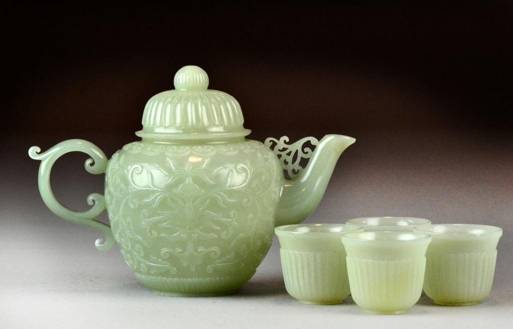 Chinese Qing Celedon Jade Mughal-styleTeaset: Finely carved to depict lotus blossoms & ruyi, to include teapot and four ribbed teacups, teapot measures 4" H, excellent condition. Property of a gentleman.