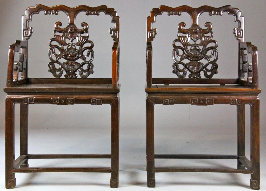 Pr. Chinese Carved Hongmu Open Armchairs: Each carved to depict bats and urn of fruit, the aprons carved as ruyi, 39"H X 23.5"W X 17.5"D, circa Guangxu Period (1875-1908). Property of a Birmingham Michigan Gentleman.