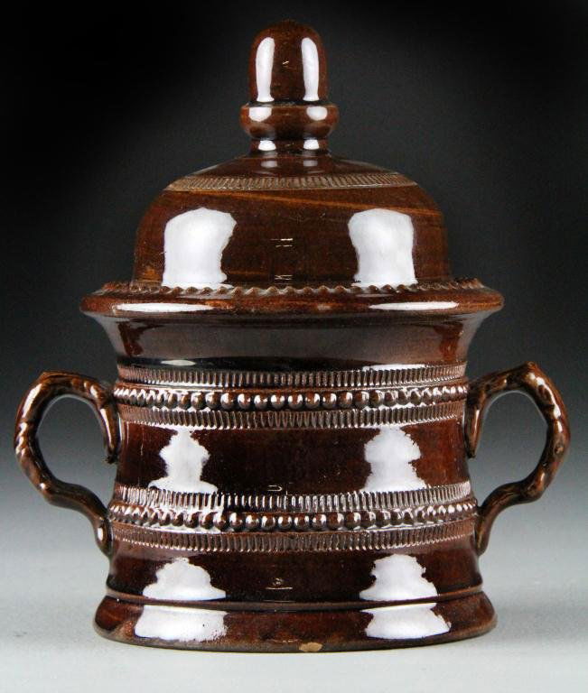 An American Redware Sugar Bowl & Cover 19thC: Having beaded and incised decoration throughout, with handles shaped as branches, and having an acorn finial. 7.75"H x 6.75"W, circa mid 19th century. Property of an Oxford Michigan Gentleman.