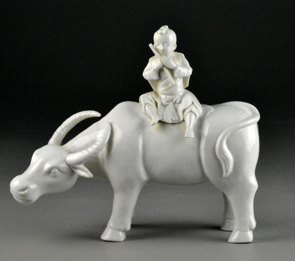 Chinese Blanc de Chine Figure: Depicting an oxen with a young Asian boy on its back with a fluteor a stick, 10" H x 11" L, circa 20th century, good condition. Private collection Mr. & Mrs. Dave Walker, Sterling Heights, Michigan.