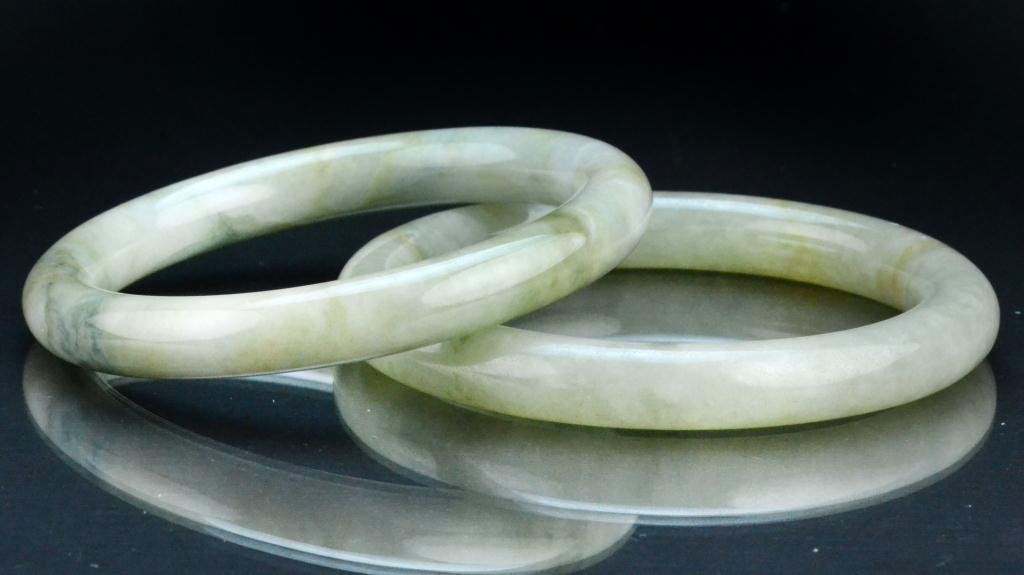 (2) Chinese Qing Jade Bangle Bracelets: Finely carved and polished the stone a light celedon with green inclusions, largest measures 3"D outside, 2.25"D inside, circa late 19th/early 20th century. Property of a Houston Texas Gentleman