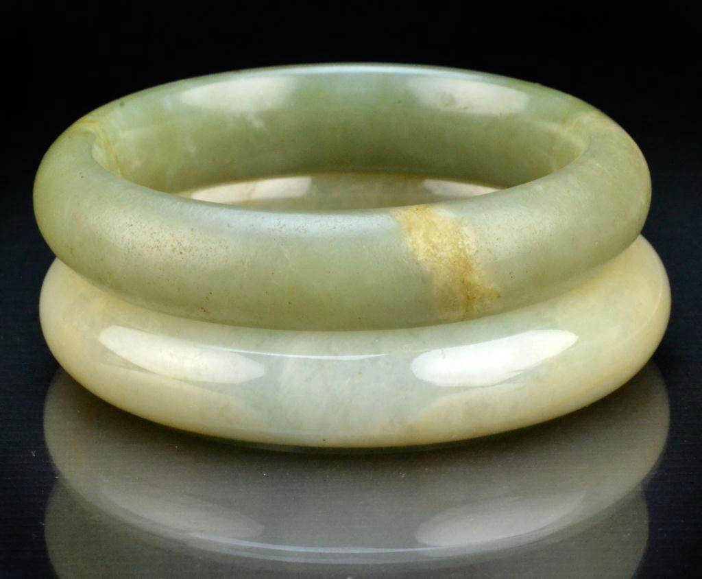 (2) Chinese Qing Jade Bangle Bracelets: Finely carved and polished the stone of one a light celedon tone, the other a medium celedon tone, largest measures 3"D outside, 2.25"D inside, circa late 19th/early 20th century. Property of a Housto