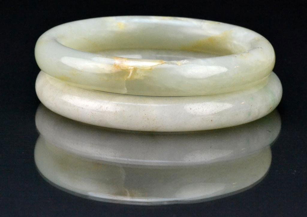 (2) Chinese Qing Jadeite Bangle Bracelets: Finely carved and polished the stone a light celedon with minimal russet inclusions, largest measures 3"D outside, 2.25"D inside, circa late 19th/early 20th century. Property of a Houston Texas Gentle