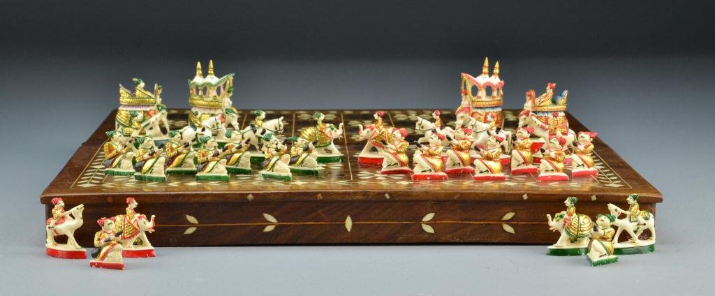 Indian Ivory Polychrome Painted Chess Set: A thirty two piece ivory chess set depicting various pieces including elephants, camels and musicians all boldly polychrome painted and finely carved, in fitted hard case which opens to a chess board