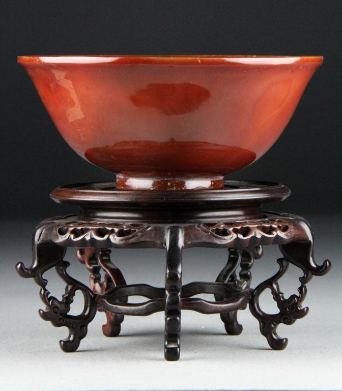 Fine Chinese Carved Carnelian Bowl: Of circular-form with slightly everted lip rim and resting on a straight foot, the stone of rich, intense color and beautifully polished, carved wooden stand, 6"D. Private collection Portland Oregon.