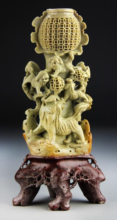 Large Chinese Soapstone Carving on Stand: Finely carved to depict foo dogs playing with toy balls carved with openwork raised on attached soapstone stand carved as a scholars rock, the stone of the carving a medium celedon tone with very fine