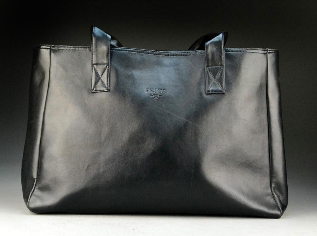 Prada Black Leather Oversized Tote: Double-handle tote with one interior zipped pouch along with black net shopping bag, 25" H x 21" W, circa 20th century. Condition: very good. Property of a Fort Gratiot, Michigan gentleman.