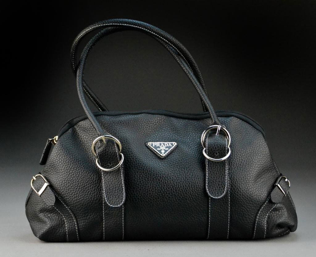 Prada Black Leather Handbag: Double-handle with white stitching, one zipped interior pocket and two open interior pockets, 16" L x 14.5" H. Condition: very good. Property of a Fort Gratiot, Michigan gentleman.