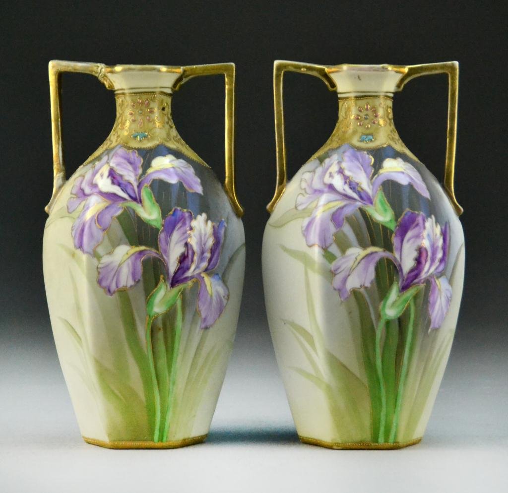 Pr. Nippon Hand Painted Porcelain Vases: Two handled paneled vases painted with iris and trimmed in gilt. 8.5" H, circa early 20th century, one handle on one vase with restoration, Green wreath mark to base. Property of a St. Clair, Michigan
