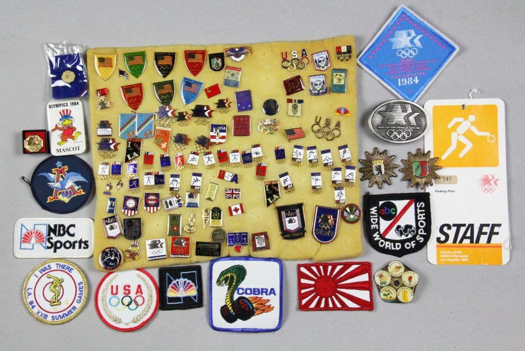 (180) 1984 Olympic Pins, Patches, Etc.: To include a wide variety of 1984 Olympic memoribilia, such as an 84 Olympic belt buckle, NBC sports pins, press pass, a total of 42 Olympic related patches, also a 139 various 84 Olympic pins represe
