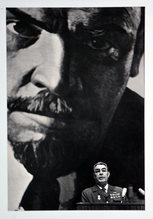 Dmitrii Baltermants Photograph Of Nikita Kruschev: Titled " Decoration and Demonstration," depicting a somber Kruschev holding up his hand, surrounded by a crowd. Gelatin silver print photograph on Agfa paper, signed and numbered 9/25, estate stamps o