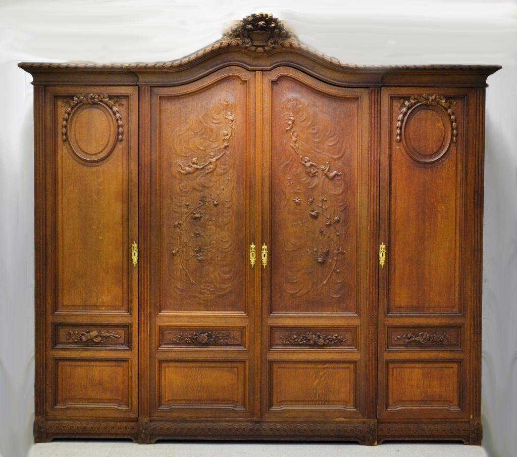 Impressive French Carved Oak Armoire: Having carved floral crest, twisted rope cornice, two doors with central wardrobe flanked by two doors with adjustable wooden shelves, central doors are carved with putti and floral decoration, small 