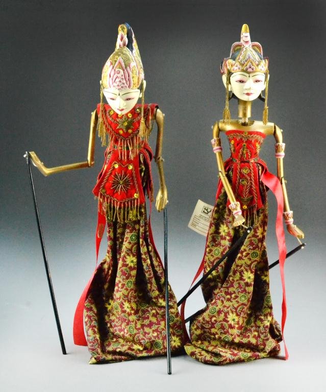 (2) Tibetan Theater Puppet Dolls: Carved and ornately painted wooden puppets, arms have black stems attached for movement, attire includes red, black and gold fabric, bead fringe, and sequin accents, one figure has tag labeled Utami Y