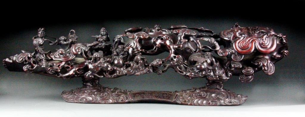 Large Chinese Rosewood Ruyi Scepter: Large horizontal piece of rosewood carved in high relief as a ruyi scepter with sprouting lingzhi and carved waves, scattered along the scepter's length and within its recesses are figures of the Eigh