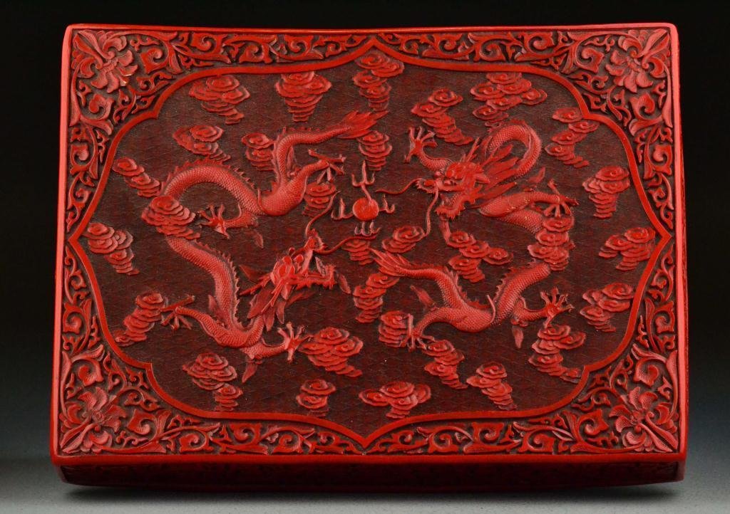Chinese Qing Carved Cinnabar Box & Cover: Finely carved and lacquered to depict two dragons chasing the flaming pearl, 2.75"H X 15.25"L X 11.25"W, circa 19th/20th century. Important West Bloomfield Michigan Collection.